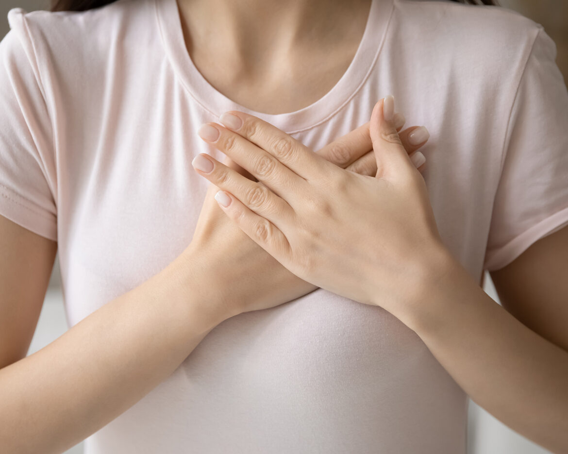 Grateful young woman applying hands on chest, expressing love