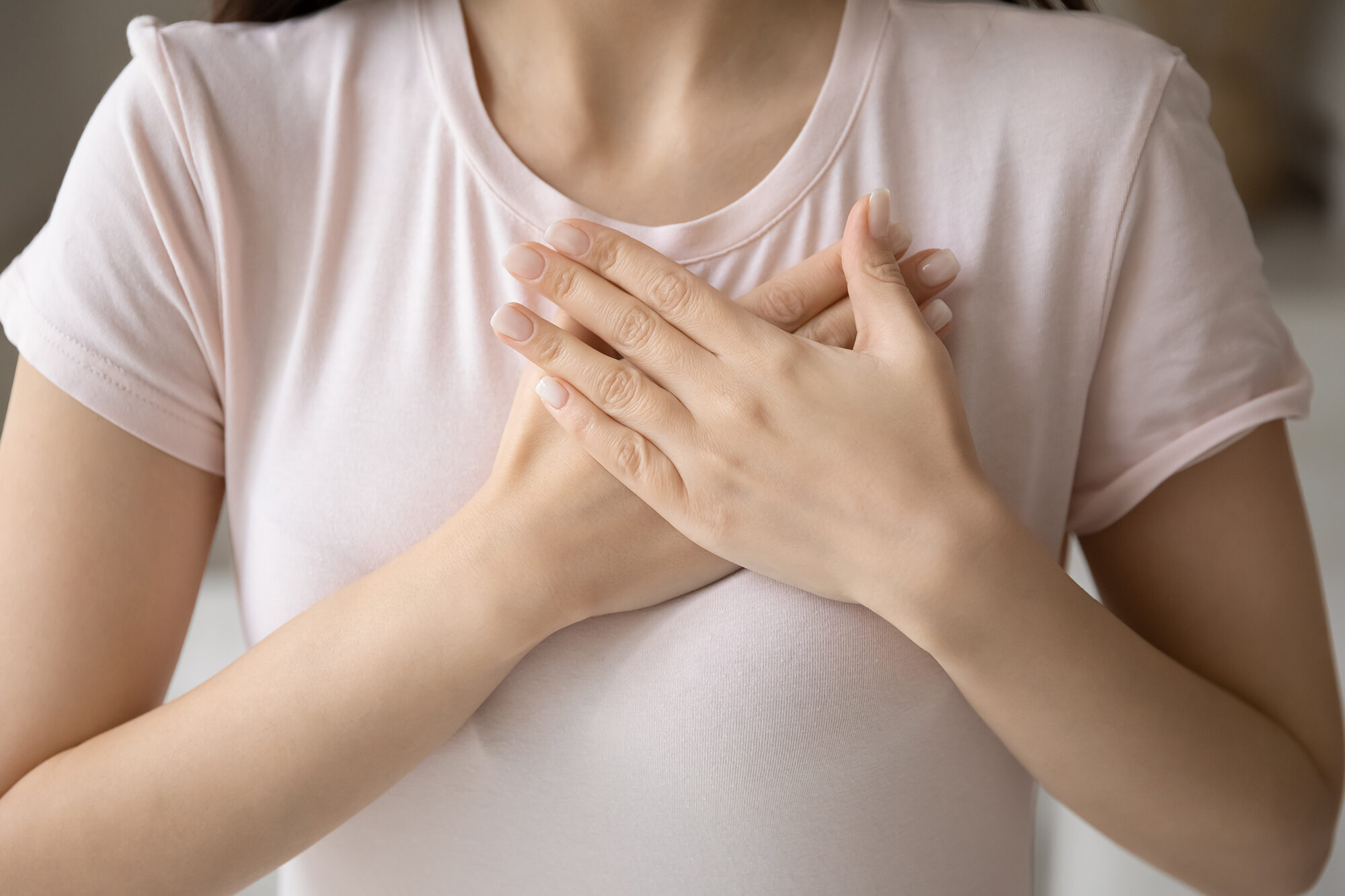 Grateful young woman applying hands on chest, expressing love